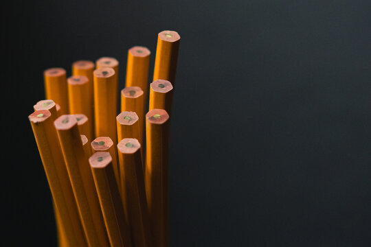 Yellow number two wooden pencils on dark blue gray background in natural light.