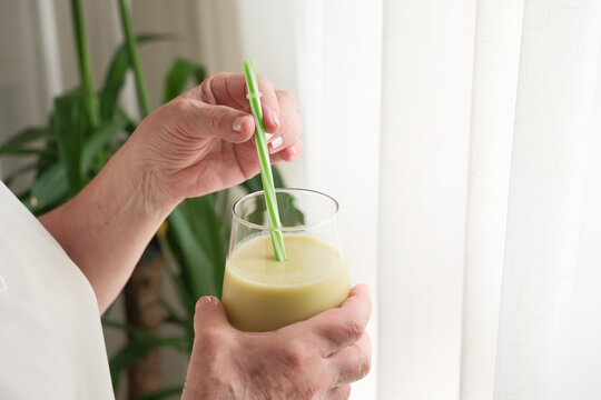 Woman holding green smoothie with a straw