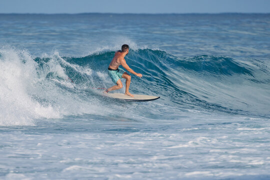 Surfer man rides a powerful blue ocean wave on a sunny day