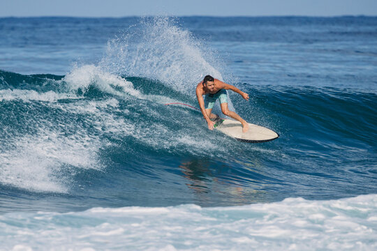 Athletic surfer riding a powerful ocean wave on a sunny day