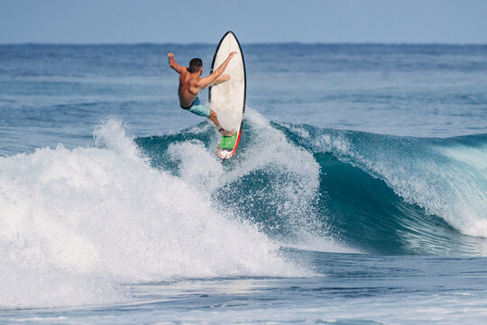 Skilled surfer performing aerial trick above ocean wave in Bali
