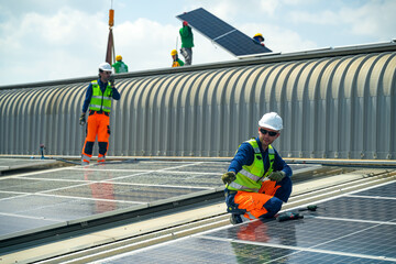 Workers install solar panels on a rooftop during daytime in a city with clear skies © FotoArtist