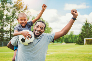 Obraz premium father with son playing football or soccer outside on field