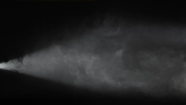 A single white spotlight shines through dense drifting smoke on a black background. Concept of overlay real effect, theater, concert, cinema, advertising, presentation, and dramatic visual design.