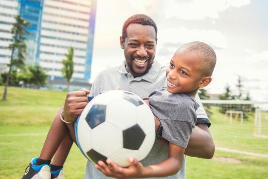 father with son playing football or soccer outside on field