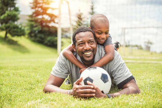 father with son playing football or soccer outside on field