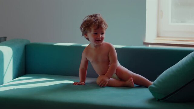 Toddler diving onto sofa cushion at home, capturing fearless play, joyful movement and active childhood adventure