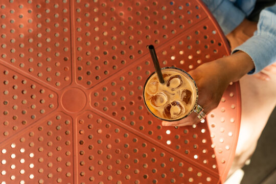 High angle view of iced espresso tonic glass on a concrete floor with patterned shadow