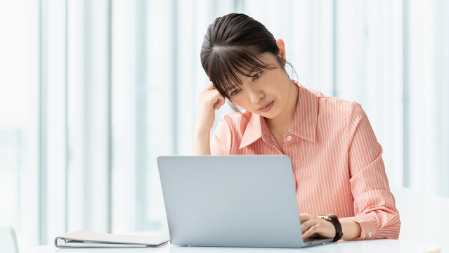 パソコンを使いながら考える女性・ビジネスウーマン, Businesswoman Thinking While Using a Laptop