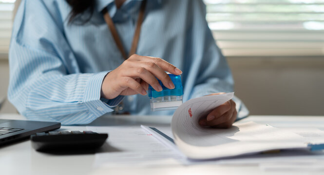 Businesswoman stamping approved contract documents, business agreement verification, notary authorization, legal approval, corporate compliance and document management concept.