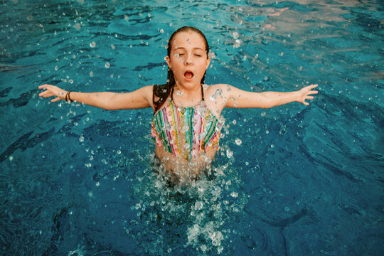 Little girl emerging from a swimming pool