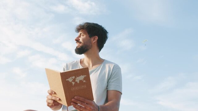 Happy young man reading an adventure notebook outdoors