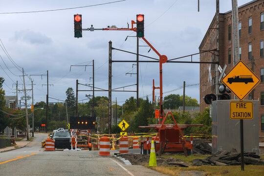 Workers manage traffic equipment for road repairs close to fire station,