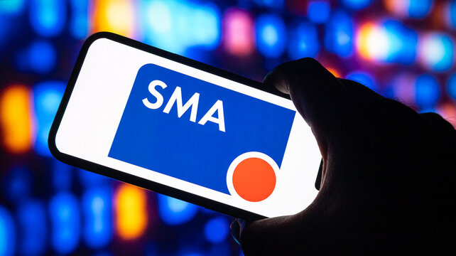 Smartphone displaying sma logo against colorful bokeh background with person holding mobile device in dark studio setting.