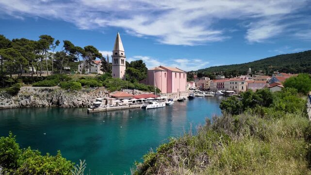 waterfront of Mali Losinj on Losinj Island,Croatia. Historic harbor with fishing boats, pastel buildings and Adriatic Sea under blue summer sky in Kvarner Bay on Adriatic coast in Kvarner Bay