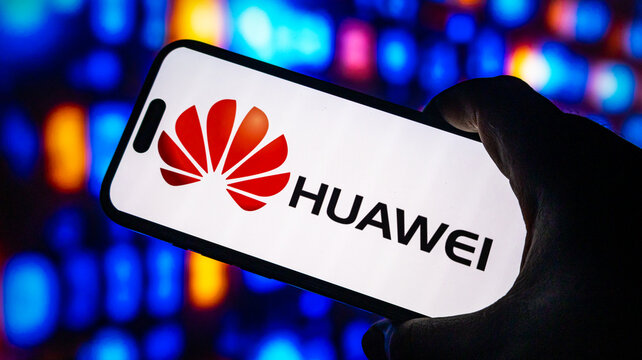 Huawei corporate logo displayed on modern smartphone screen held by person with vivid blurry bokeh background light effect.