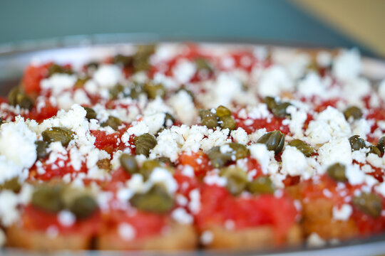 Traditional Greek appetizer topped with tomato, feta cheese, and capers, served as a fresh Mediterranean dish in Milos, Greece.