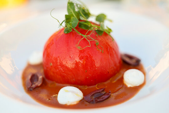 Traditional Greek stuffed tomato served with olives, herbs, and creamy cheese, presented as an elegant Mediterranean restaurant dish.