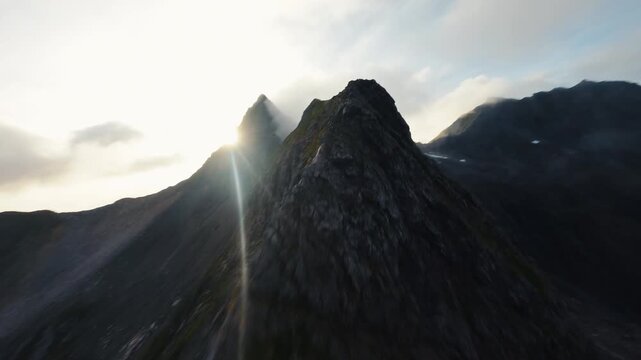 FPV Drone Sweeping Fast Along Steep Jagged Mountain Ridge in Fog