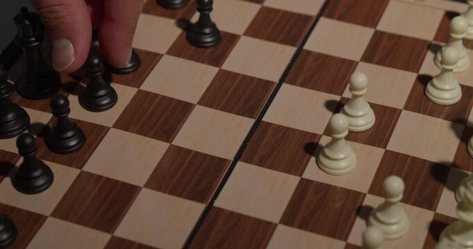 hand moving chess piece on wooden board