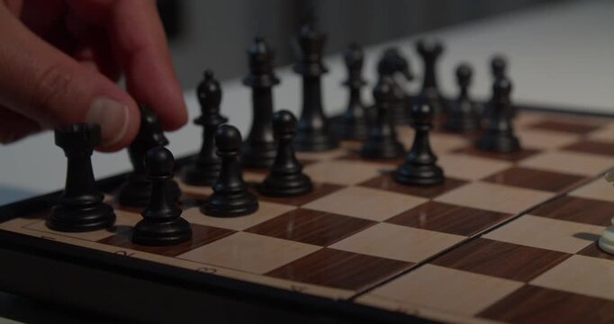 close up of a hand moving a chess piece on a board