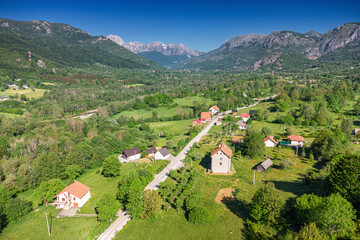 Obraz premium Aerial drone view of a small mountain village road winding through green valley. Travel concept.