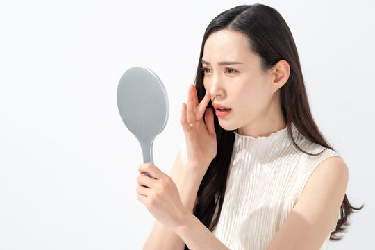 鏡を見て鼻を気にする女性