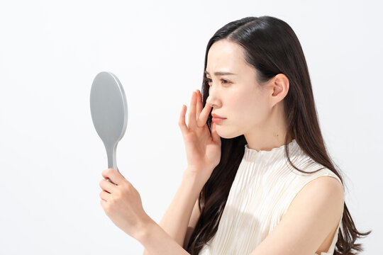 鏡を見て鼻を気にする女性