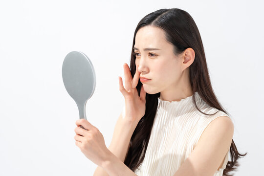 鏡を見て鼻を気にする女性