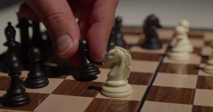 close up of a hand moving a chess piece on a board