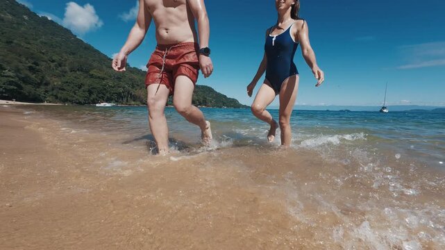Young couple of man and woman walk from the tropical sea