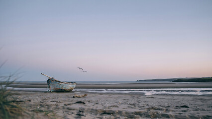 Obraz premium An old wooden boat rests on a sandy beach at sunset isolated on a transparent background