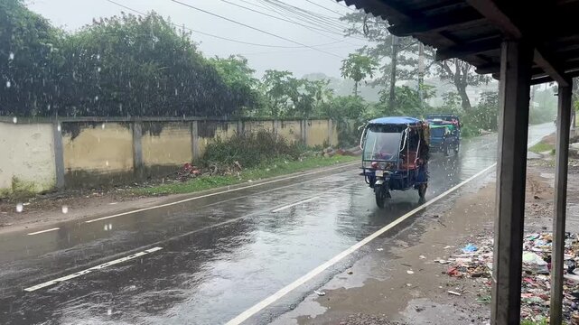 Rain-Soaked Highway Scene: Vehicles and Three-Wheeler Driving in Heavy Monsoon Storm