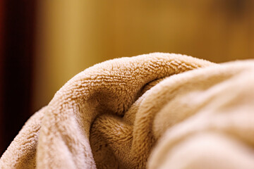 Close-Up Macro Texture of Soft Beige Fleece Blanket Folded with Warm Lighting © Abulail