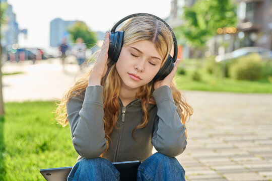 Young woman listening to music in black wireless headphones with eyes closed