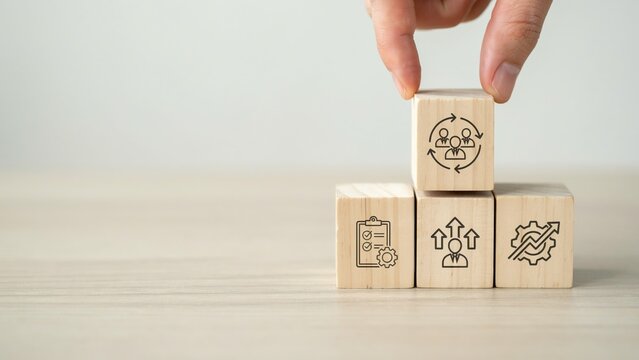Hand placing a wooden block with a team collaboration icon on top of others