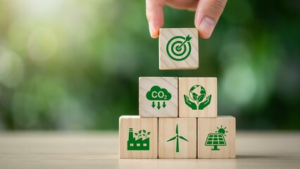 Hand stacking wooden blocks with environmental icons for sustainable development