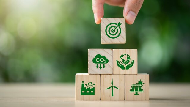 Hand stacking wooden blocks with environmental icons for sustainable development