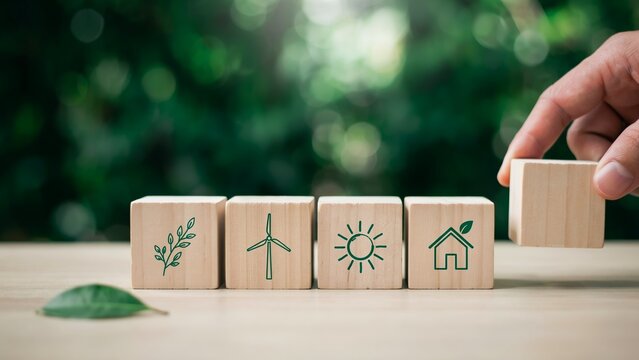 Hand placing wooden block with ecofriendly icons for sustainable development