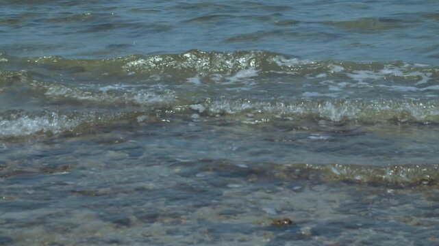Waves crashing on a dirty beach with fishing boats