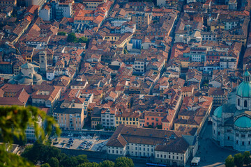 Obraz premium Aerial view of Como, Italy showcasing terracotta rooftops, narrow streets, and historic buildings under clear blue sky