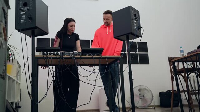 Man and woman in music studio reviewing DJ mixing notes and working with soundboards. DJ, music studio, notes, soundboard, review