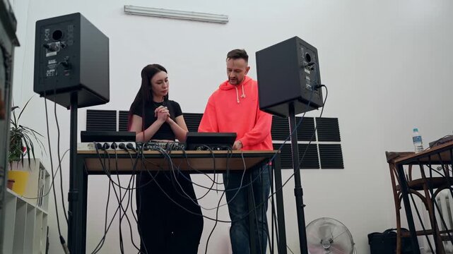 Music lesson with two DJs discussing sound mixing approaches at studio console. DJs, music lesson, studio, discussion, mixing