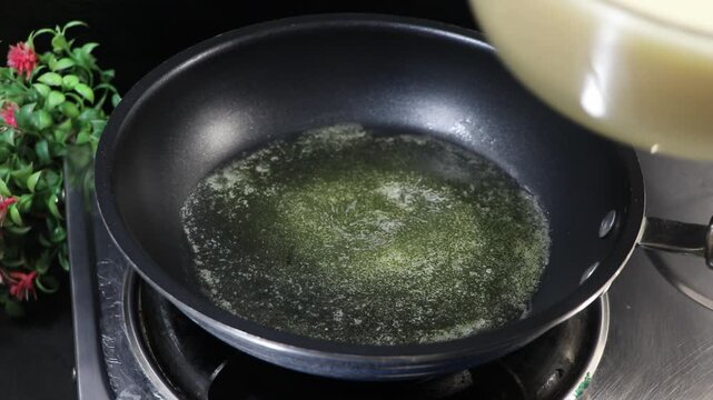 Person pouring a frothy egg mixture into a frying pan with melted butter
