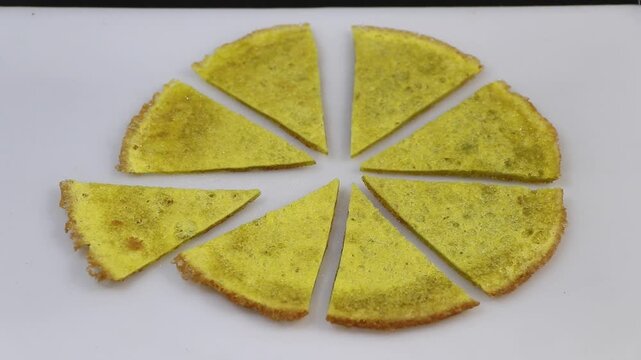 Hand picking a triangular slice of omelet arranged like a pizza
