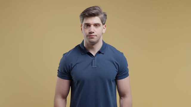 Young man shaking his head to say no in a studio portrait on a yellow background. Disagreement, rejection, refusal, negative response, decision making and communication.