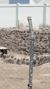 Panning shot of fenced ancient stone walls at an active archaeological excavation site.
