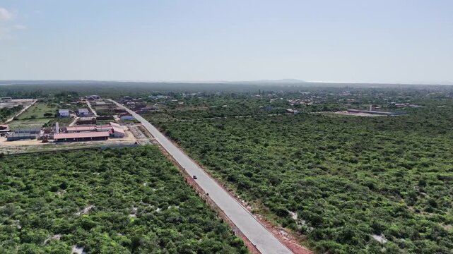 Aerial View of Road Leading to Coastal Town with Dunes on the Horizon