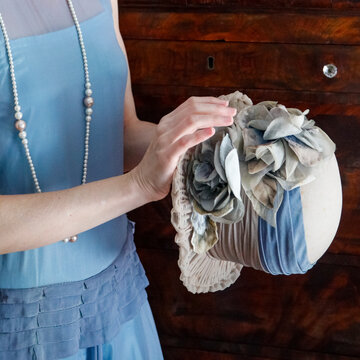 Woman dressed in vintage attire holding a 1920s hat