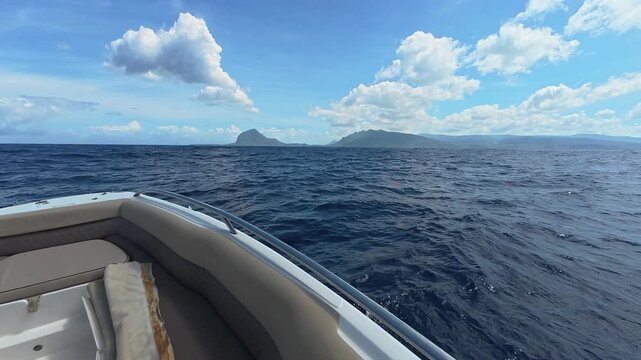 View from a motorboat cruising on the deep blue ocean towards tropical islands